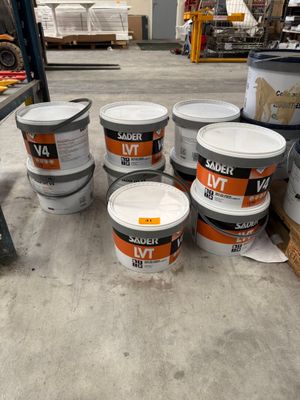 plusieurs seaux de peinture posés sur une palette dans un entrepôt