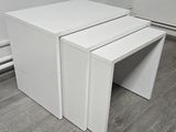 trois tables blanches empilées les unes sur les autres sur un plancher en bois