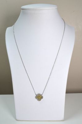 collier jaune et argenté avec un pendentif en forme de fleur sur un mannequin blanc