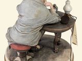 a figurine of a woman sitting at a table with a lamp