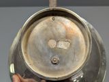 a person holding a silver pot with a wooden handle