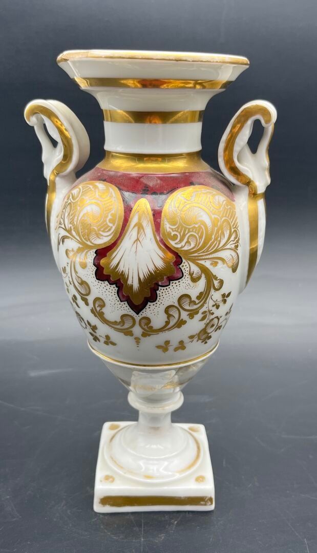 PARIS Un vase médicis en porcelaine à décor doré et bordeaux rocaille. H 22,5 cm. (réparations, manques)