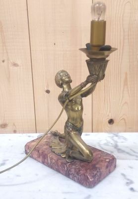 une statue représentant une femme tenant une bougie, posée sur un socle en marbre