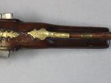 a wooden gun with brass decorations on it on a white surface