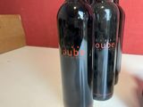 three bottles of red wine are lined up on a table