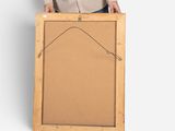 smiling man holding up a blank picture frame against a white background