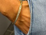 the woman is wearing a gold bracelet and a blue jean shorts