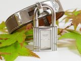 a silver padlock and a brown leather belt on a white surface