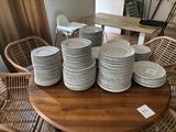 a lot of plates on a table with chairs in the background