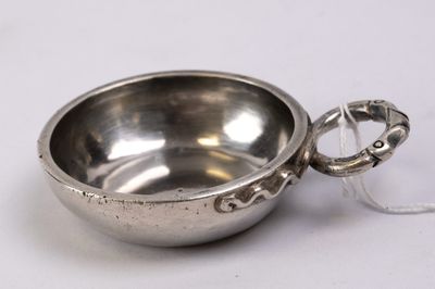 a small silver bowl with a handle on a white surface