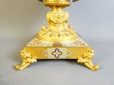 a gold vase with a bird on top of it