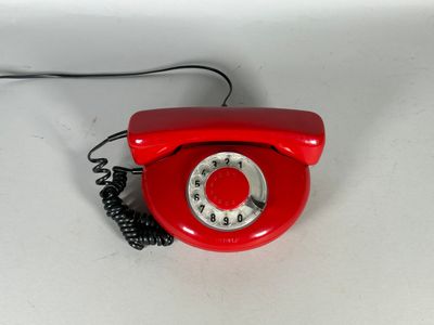un téléphone rouge posé sur une surface blanche, muni d'un cordon