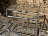 a glass table and two chairs in front of a brick wall