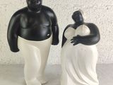 two figurines of a man and a woman standing next to each other