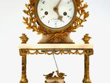 une horloge posée sur une étagère, sur laquelle se trouve un oiseau