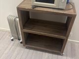 a microwave sitting on a wooden shelf in the corner of a room