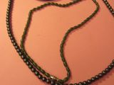 un collier et une paire de ciseaux posés sur un fond rose