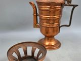 an old copper coffee pot and a cup on a white surface