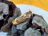 une bague en or posée sur un tas de fleurs séchées