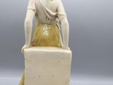 an antique figurine of a woman sitting on a box