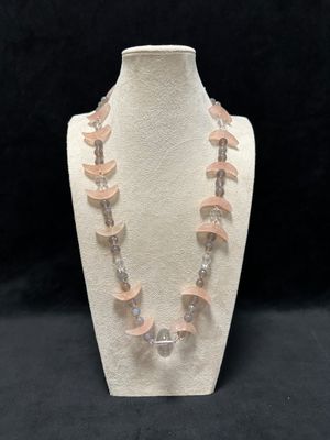 a close up of a necklace on a mannequin on a black background