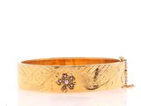a close up of a gold bracelet on a white background