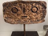 an image of a sculpture of a face on top of a wooden block