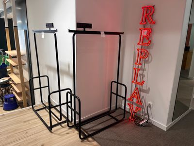 une enseigne au néon rouge accrochée au mur, à côté d'un porte-vêtements noir