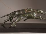 a statue of two dogs running with a kite in the air