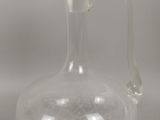 une bouteille en verre transparent avec une anse, posée sur une table
