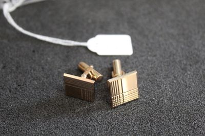 une paire de boutons de manchette en or avec une étiquette sur un fond noir