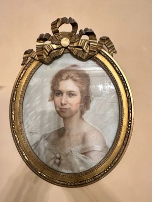 portrait of a woman in a white dress in a gold frame on a wall
