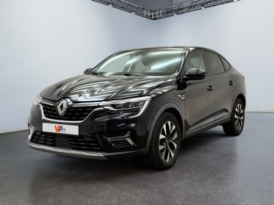 Une voiture noire est garée dans une grande pièce aux murs blancs.