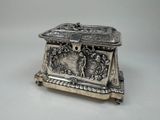 an antique silver box with a bird on it on a table