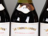 three bottles of wine are lined up on a shelf