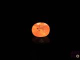an orange stone on a black surface in the dark