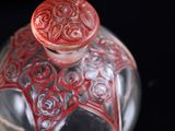 a glass bottle with a red lid on a black surface
