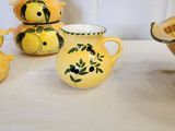 five yellow vases and a bowl of lemons on a table