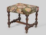 an old stool with a floral upholstered seat and wooden legs