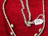 un collier et des boucles d'oreilles posés sur un tissu rouge, avec une étiquette de prix