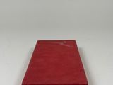 a red book sitting on top of a white table next to a white wall