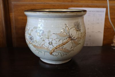 un vase posé sur une table, avec un mot en arrière-plan