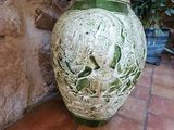 a green vase with a handle on a tiled floor