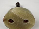 an image of a green jade bell with two holes in the middle