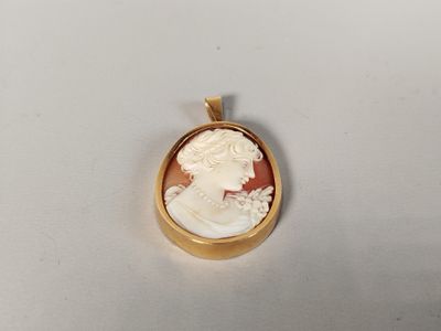 a close up of a gold plated pendant with a woman ' s face