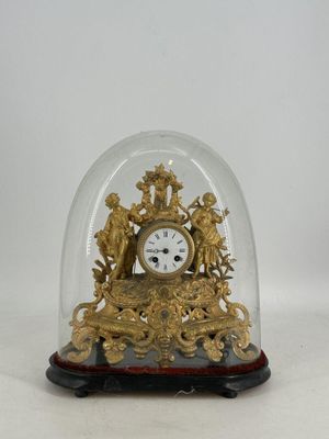une horloge en or sous un dôme de verre sur une table