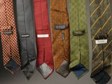 several different colored ties hanging from a rack on a wall