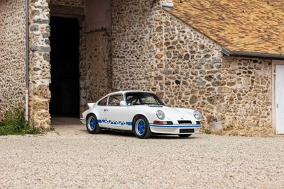 a small white car parked in front of a stone building