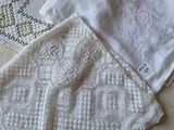 trois nappes blanches au crochet posées côte à côte sur un lit