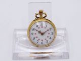 une petite montre de poche en or présentée dans un coffret transparent